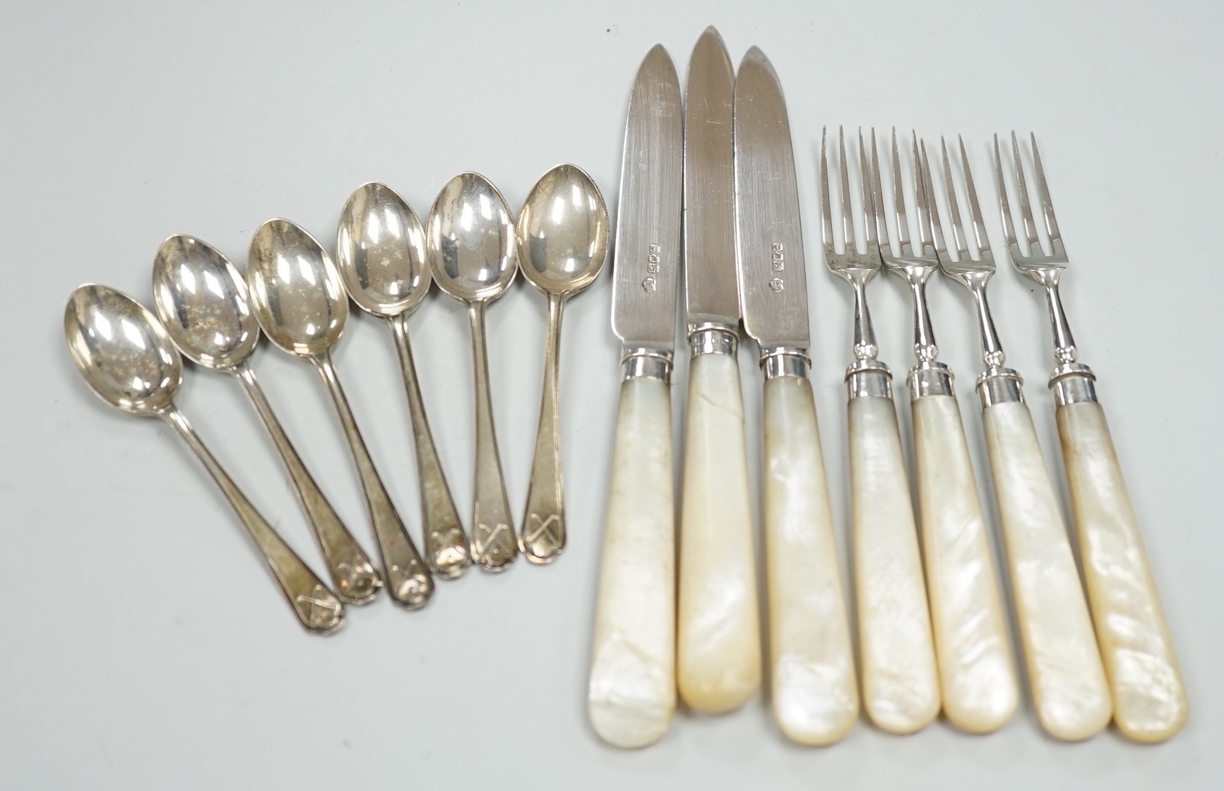 A set of six George V golfing related teaspoons, Walker & Hall, Sheffield, 1933 and seven mother of pearl handled silver dessert eaters.